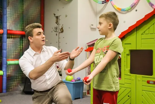 Bartosz Rybczyński zapraszający chłopca do udziału w pokazie magii dla dzieci