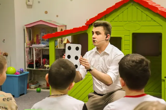 Dzieci obserwujące z bliska pokaz iluzjonisty Bartosza Rybczyńskiego w sali zabaw