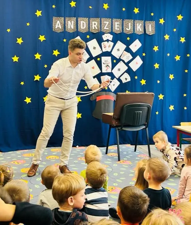 Bartosz Rybczyński podczas pokazu magii dla dzieci na tle dekoracji andrzejkowej