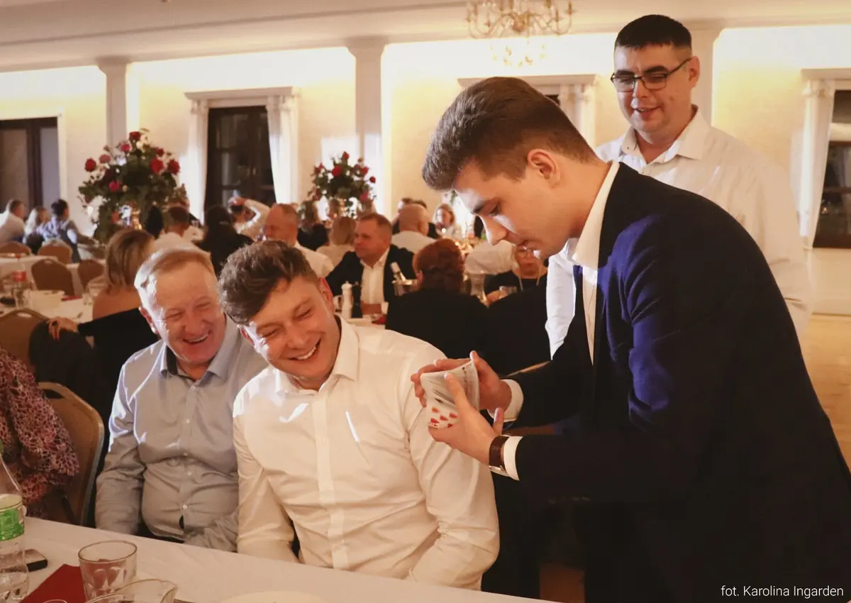Bartosz Rybczyński prezentujący iluzję gościom przy stole podczas imprezy firmowej