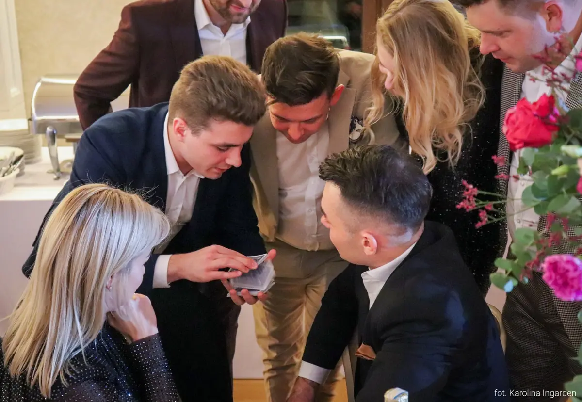 Uczestnicy eventu oglądający z bliska występ iluzjonisty Bartosza Rybczyńskiego