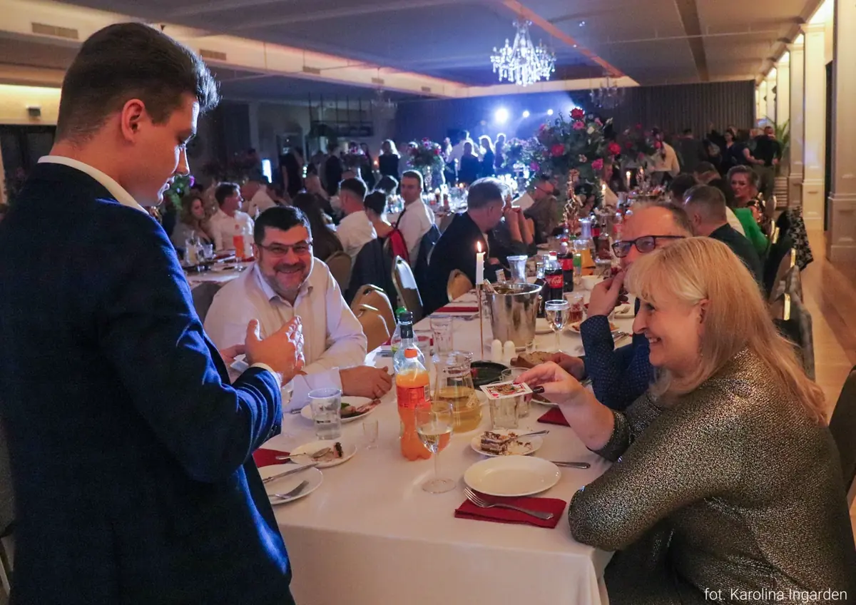 Iluzjonista Bartosz Rybczyński występujący przy stołach gości firmowego bankietu