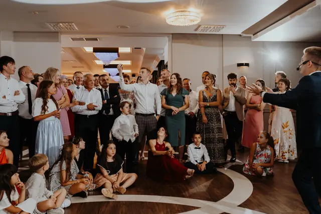 Goście weselni zebrani na parkiecie podczas występu iluzjonisty Bartosza Rybczyńskiego