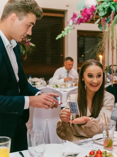 Iluzjonista Bartosz Rybczyński występujący przy stoliku gości weselnych